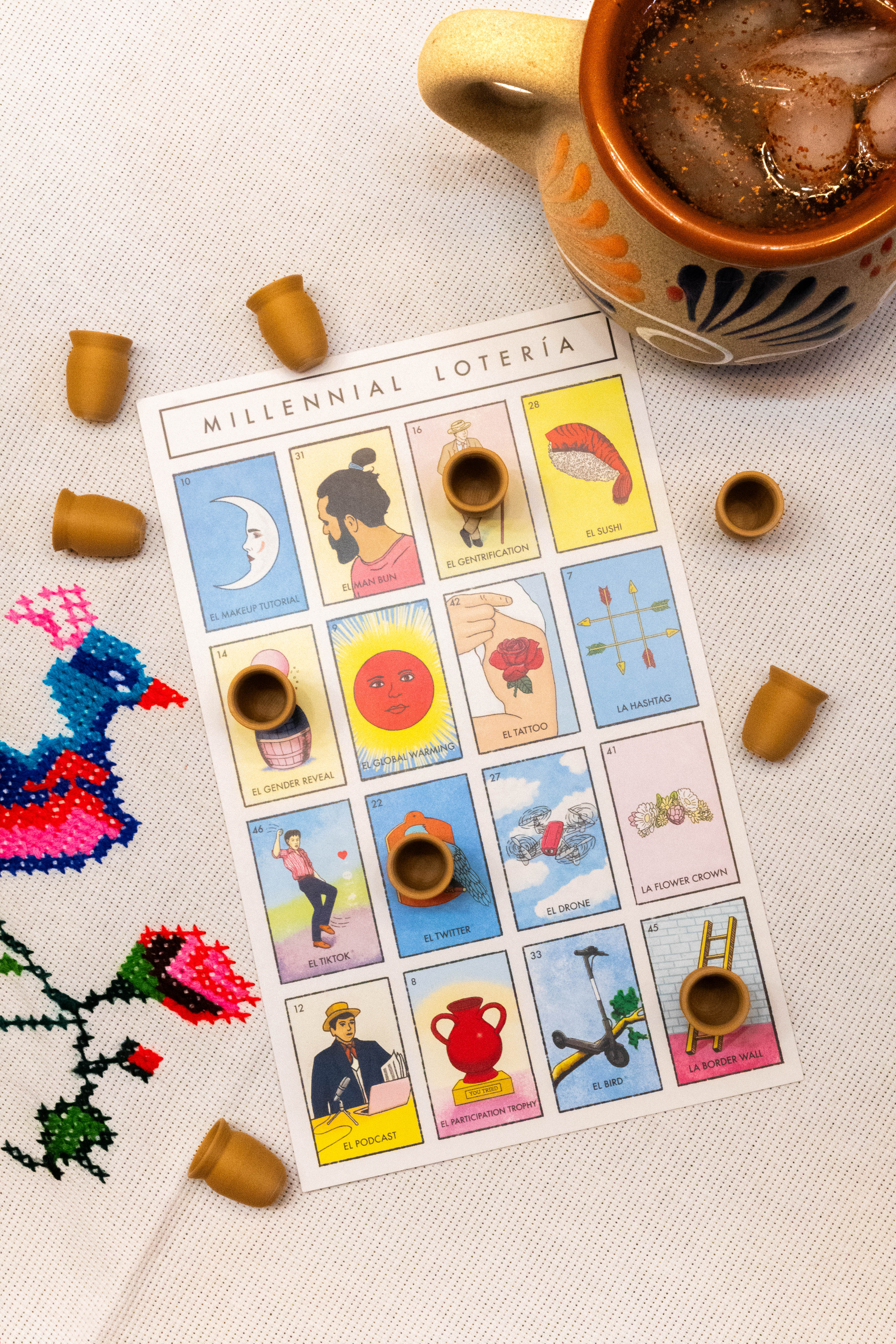 Chicharrón fichas beside a lotería board and a drink